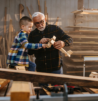 Grandfather making a wooden plane with his grandson
